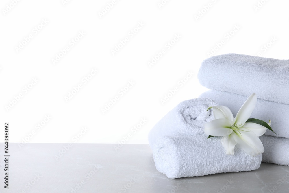 Fresh towels and lily flower on light grey marble table against white background. Space for text Fresh towels and lily flower on light grey marble table against white background. Space for text
