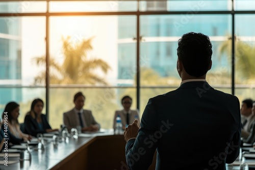 A man confidently stands in front of a group of people in a conference room, engaging in a discussion or presentation, Businessman pitching to potential investors in a boardroom, AI Generated