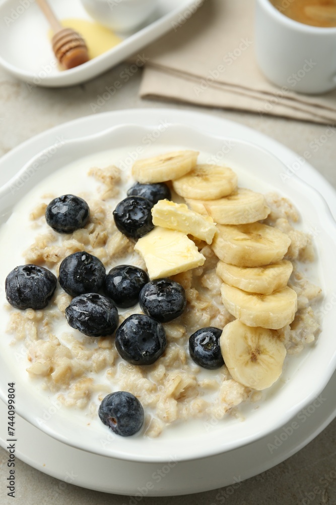 Tasty oatmeal with banana, blueberries, butter and milk served in bowl on light grey table, closeup Tasty oatmeal with banana, blueberries, butter and milk served in bowl on light grey table, closeup