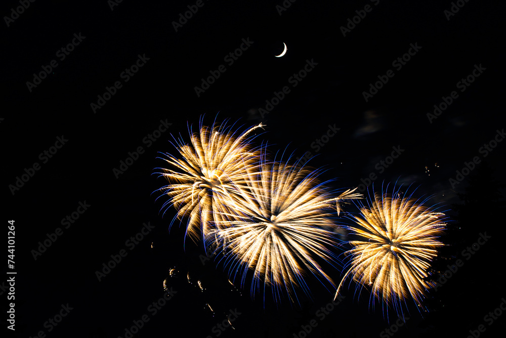 Montreal, Canada - June 25 2022: Fire works show with quarter moon in background at La Ronde in Montreal Montreal, Canada - June 25 2022: Fire works show with quarter moon in background at La Ronde in Montreal