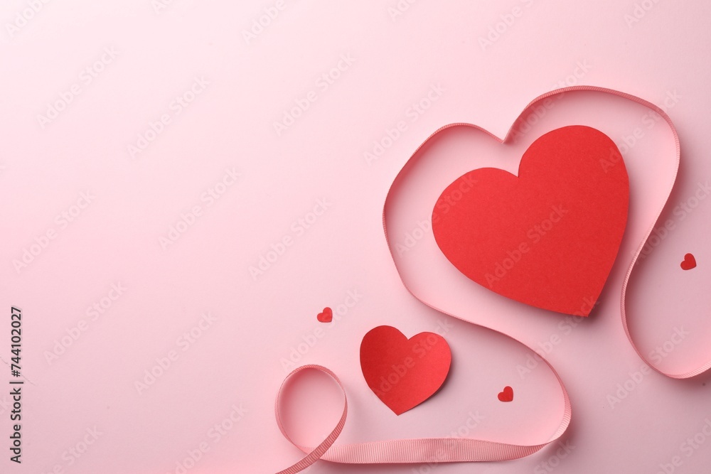 Paper hearts and ribbon on pink background, flat lay. Space for text Paper hearts and ribbon on pink background, flat lay. Space for text