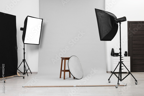 Stool with light reflector surrounded by professional lighting equipment in photo studio photo