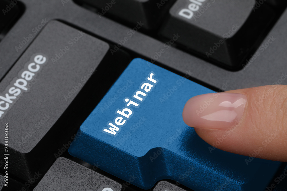 Woman pressing blue button with word Webinar on computer keyboard, closeup Woman pressing blue button with word Webinar on computer keyboard, closeup