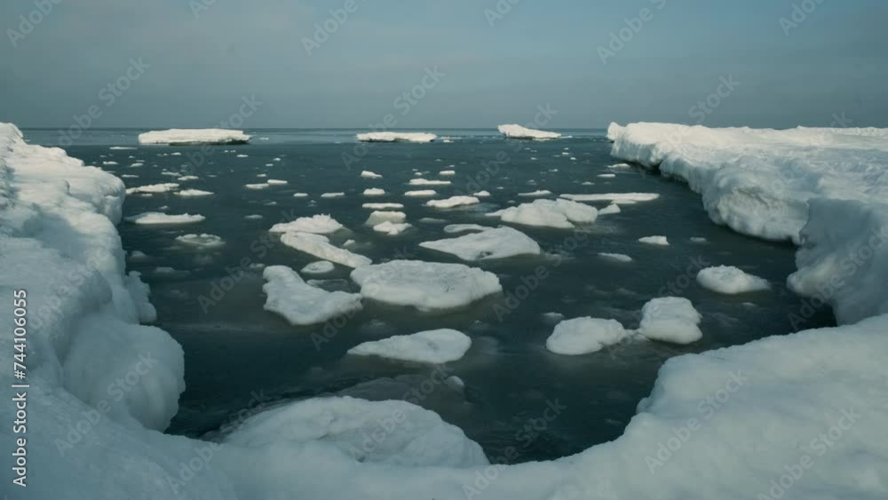 Real time of frozen cold ocean with ice floating on surface in winter on gloomy day