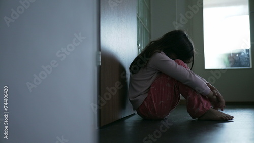 Struggling child sitting on corridor floor covering face feeling loneliness and solitude during difficult times. Childhood depression