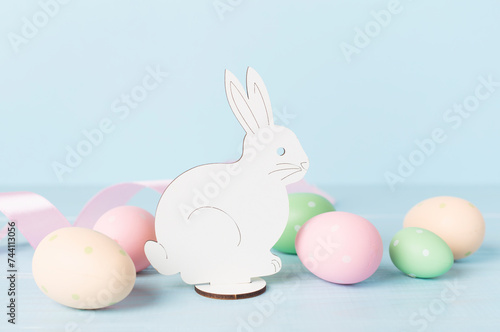 Easter eggs and rabbit on color background