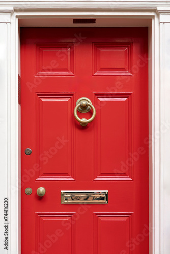 Vibrant red door on a classic white facade, exuding warmth and timeless elegance.