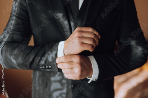 young smiling man buttoning up his jacket in the morning before the wedding. close-up of a man in a business suit. Businessman puts on a suit. A man fastens the buttons on his jacket.