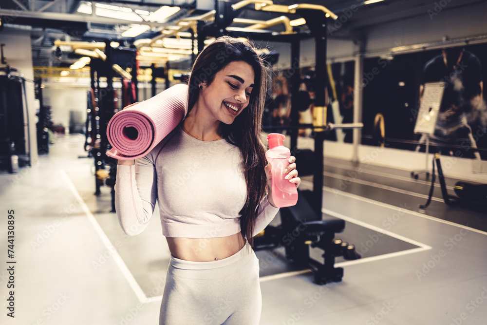 Shot of a young woman drinking a bottle of water at the gym. Shot of a young woman drinking a bottle of water at the gym.
