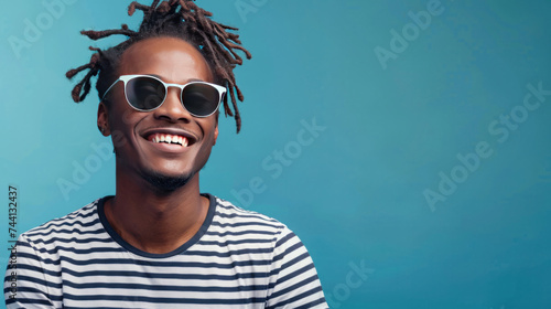 Portrait photograph of a young man smiling, dressed in stylish sunglasses and a striped t-shirt © yganko