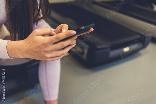 Shot of a young beautiful woman using her cellphone after her workout at the gym.