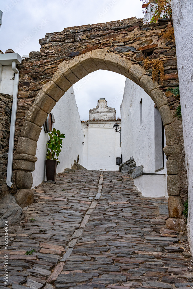 Naklejka premium Stone arch in the beautiful white street of the fortified village of Monsaraz in Alentejo region of Portugal.