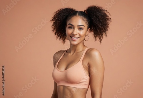 A young woman with voluminous curly hair and a sports top, smiling warmly and looking to the side. She represents health and vitality.