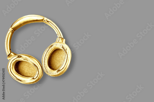 Big modern golden headphones isolated on grey background. Minimal concept. Copy space for the text