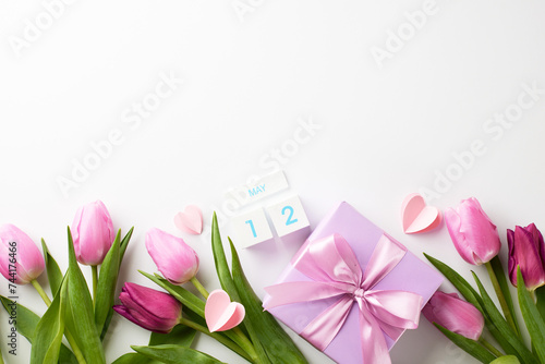 Fototapeta Naklejka Na Ścianę i Meble -  Mother's Day tribute: blossoms and bow of appreciation. Top view of tulips, heart-shaped paper decor, calendar block with 