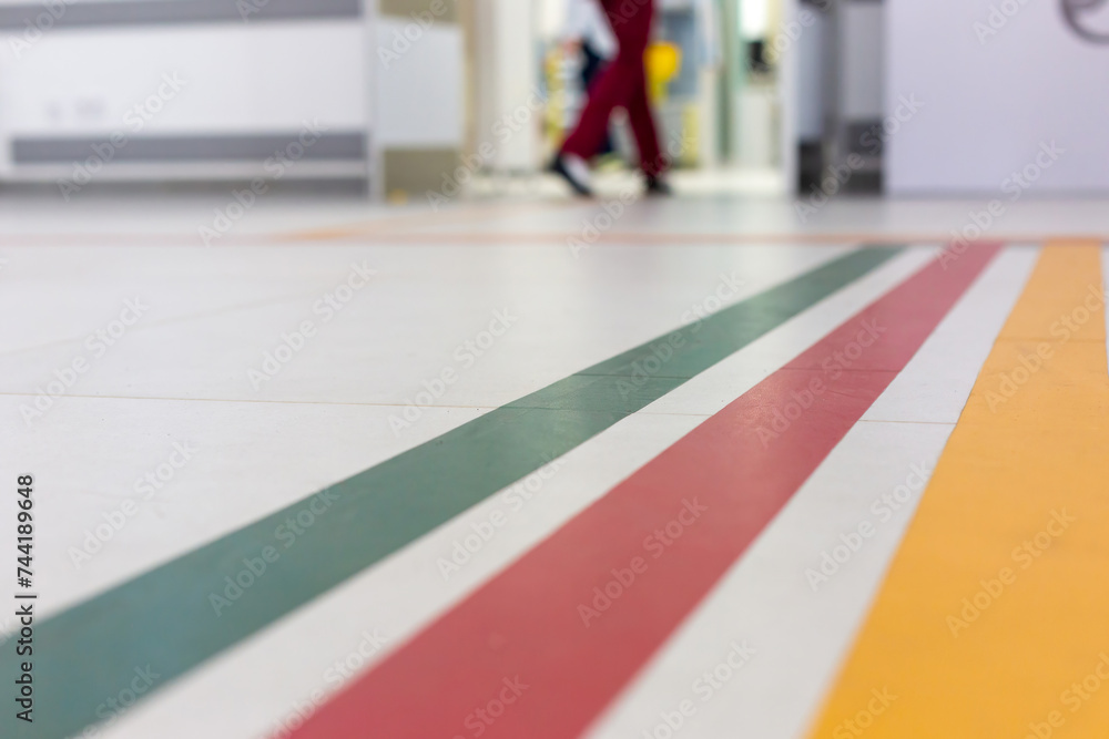 Colorful guide lines on the floor of the hospital corridor for navigation with a blurred hospital background