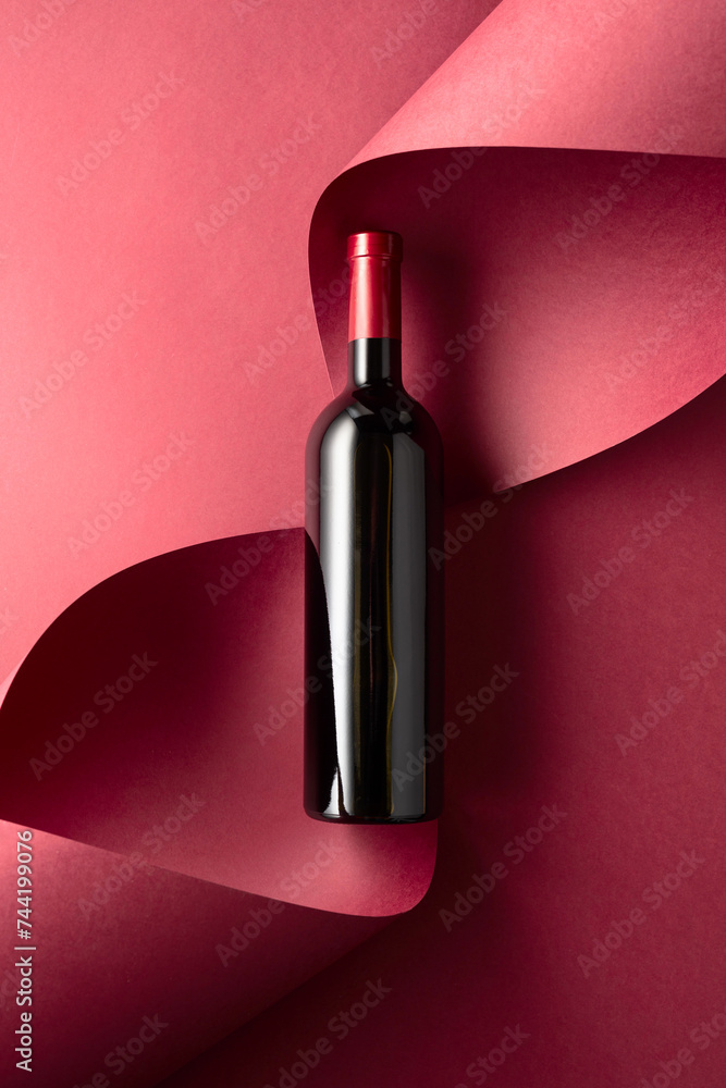 Fototapeta premium Bottle of red wine on a red background.