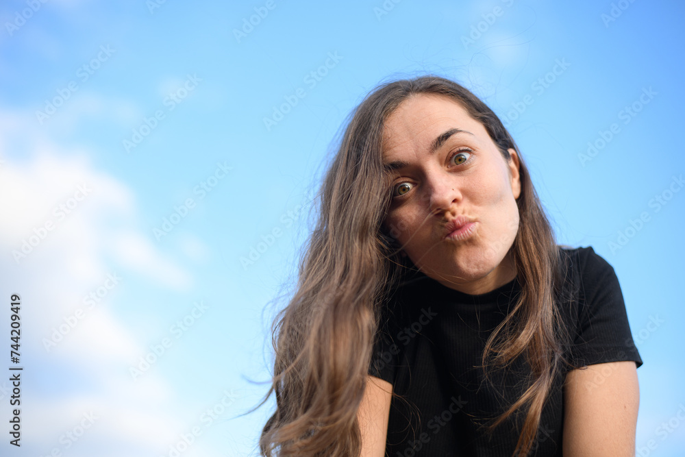 young Caucasian girl with an happy face against a blue sky background young Caucasian girl with an happy face against a blue sky background