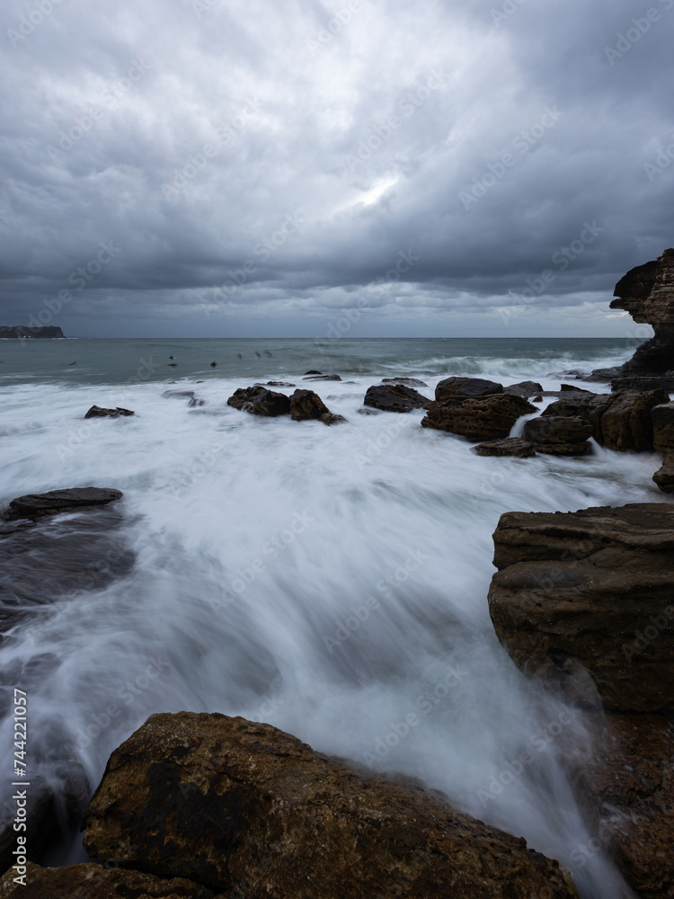 Wave water flowing into the rocky channel at the beach.