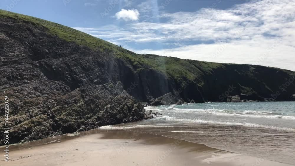 Sandy beach in Wales in front of rugged rocky coastline in Cardigan Bay looming above Sandy beach in Wales in front of rugged rocky coastline in Cardigan Bay looming above