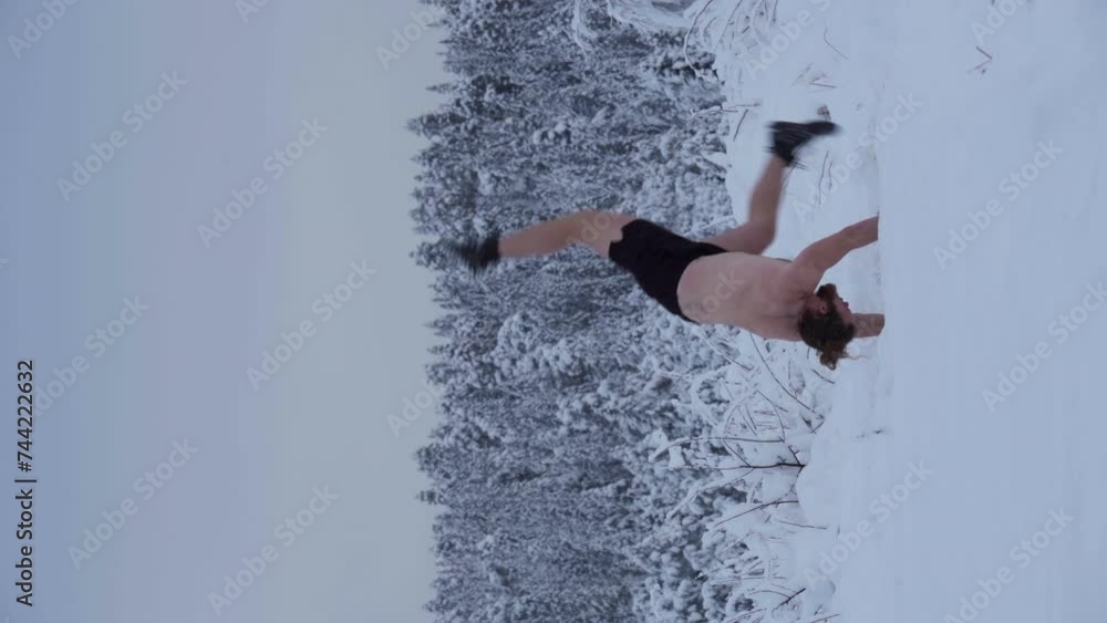 A Man is Executing a Handstand Amidst the Deep Snow - Vertical Shot
