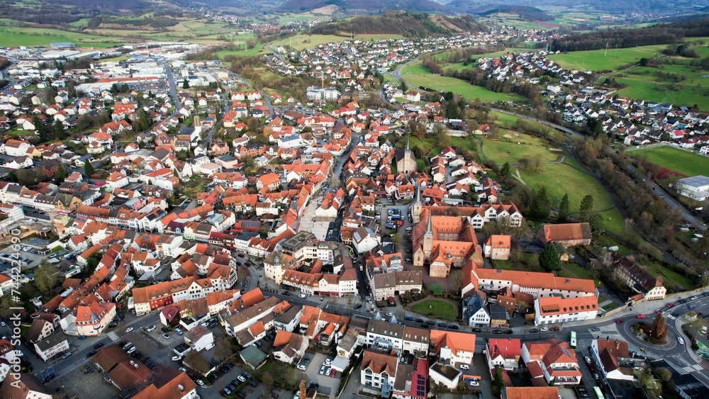 Aerial around the old town of the city Schlüchtern in Hesse, Germany on a sunny day day in winter