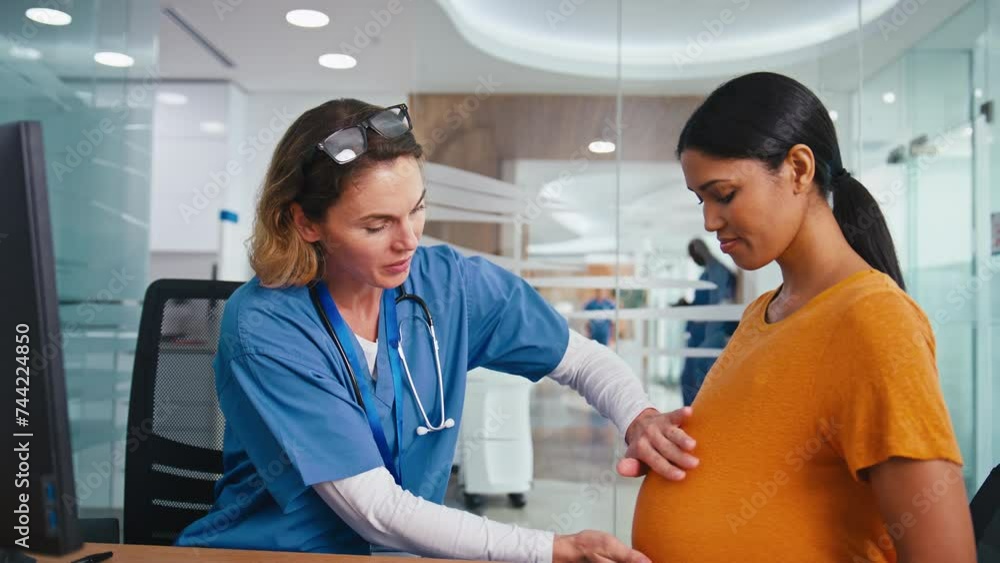 Female Nurse Or Doctor Wearing Scrubs Examining Pregnant Woman In Hospital Obstetrics Clinic Female Nurse Or Doctor Wearing Scrubs Examining Pregnant Woman In Hospital Obstetrics Clinic