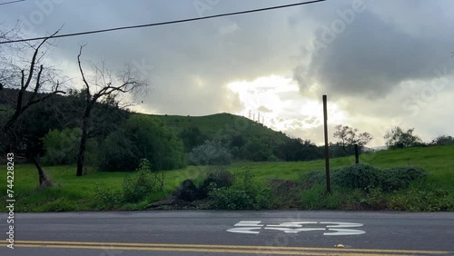 A nice dark and colorful dusk setting as a storm approaches, we see dead trees and golden hills in the distance. Gloomy rain clouds over an old lonely road in Alpine California. photo