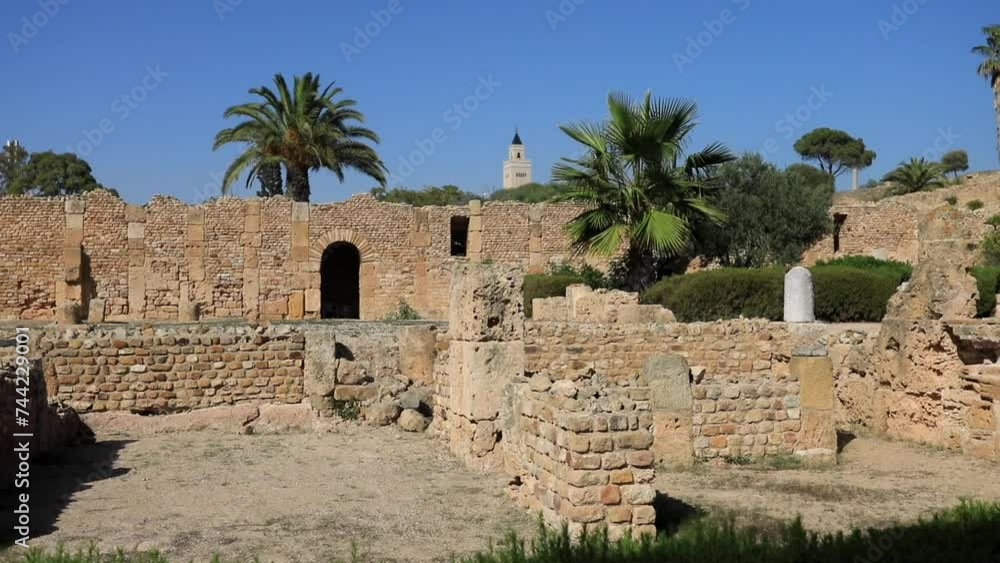 Ancient Roman ruins in Carthage, Tunisia with palm trees under blue sky Ancient Roman ruins in Carthage, Tunisia with palm trees under blue sky