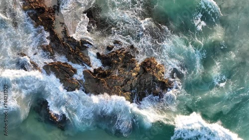Top down static shot of Stradbroke Islands Rocky Coast Line. Waves hitting the rocks out at sea, Golden Hour Shot of Waves Crashing into Rocks in slow motion Drone shot. 4K QLD Australia Tourism photo