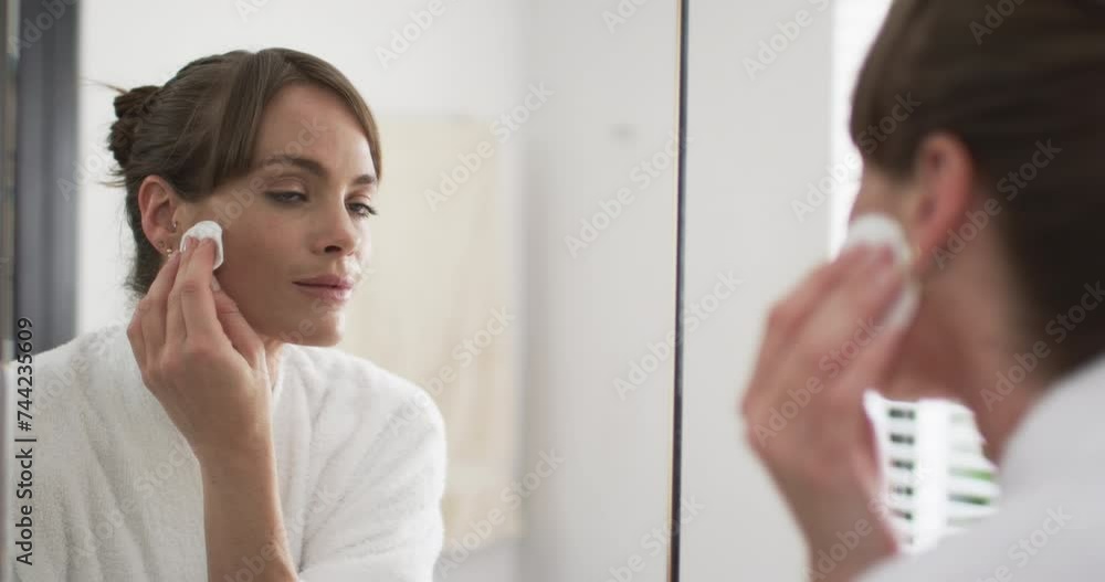 Middle-aged Caucasian woman applies skincare in a home bathroom Middle-aged Caucasian woman applies skincare in a home bathroom