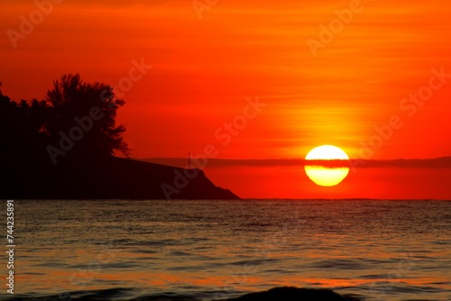 Tranquil beach setting with a stunning sunset view, the horizon line marked with the water