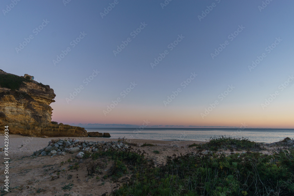 Beach and rock formation in front of the atlantic sea in evening twilight after sunset at Figueira beach, Vila do Bispo, Algarve, Portugal