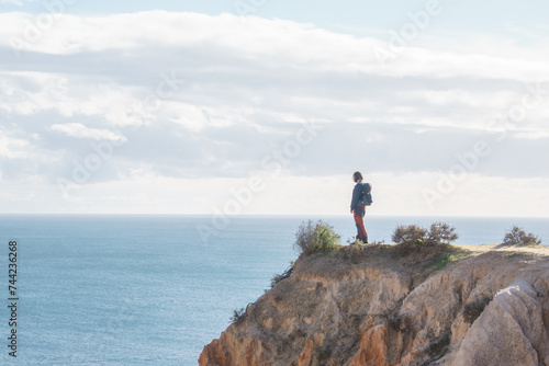 Tourist standing on golden rock cliffs at the coastline of the Atlantic Ocean with near the Cave of Benagil  Algarve  Portugal