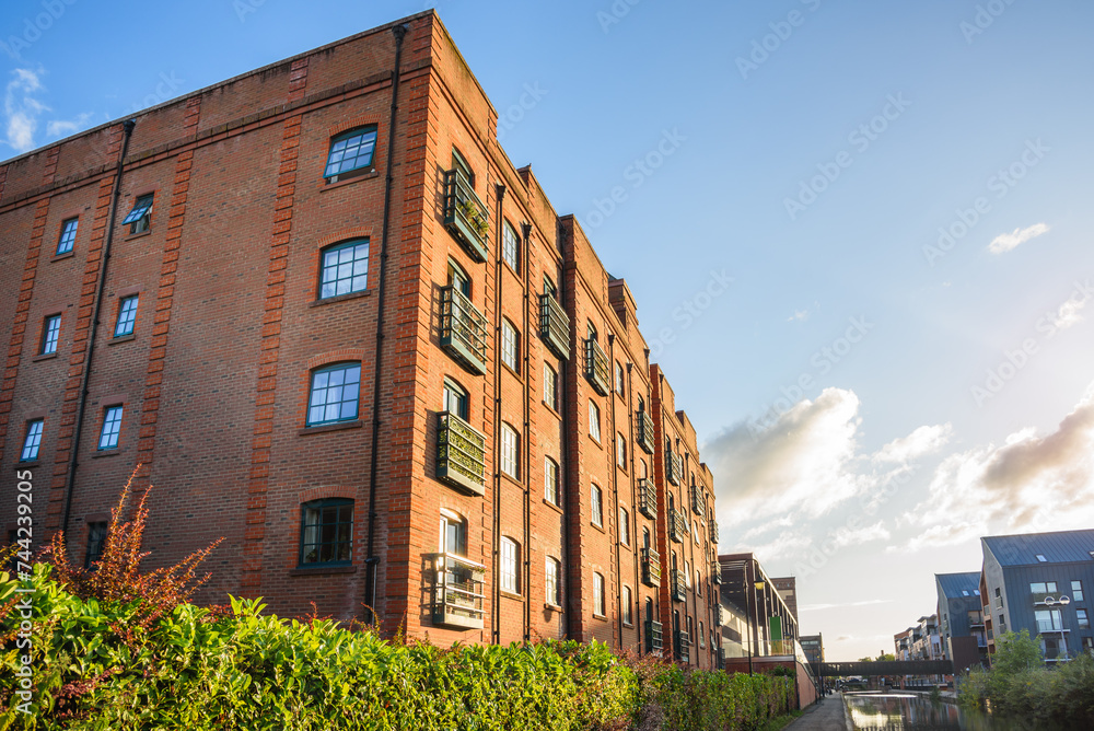 Low angle view of a brick apartment building alog a canal under blue sky at sunset