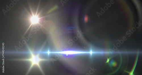 Image of spotlight with lens flare and light beam moving over dark background © vectorfusionart