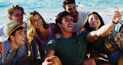 Image of emoji icons flying up with a group of young Caucasian friends taking a selfie on a beach in