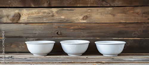 Three white bowls with handles are neatly arranged on top of a wooden table, creating a simple and elegant display.