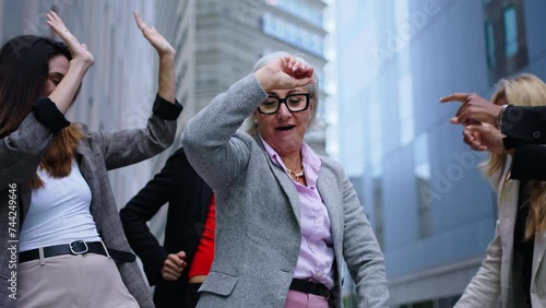 Group of excited business women diverse ages dancing outside the office center having fun enjoying and celebrating success at work. Female people entrepreneur and happy lifestyle concept. Slow motion 