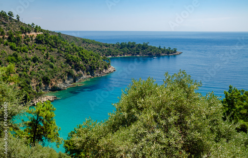 Serene blue lake nestled among lush forests and towering mountains in Thassos, Greece © Wirestock