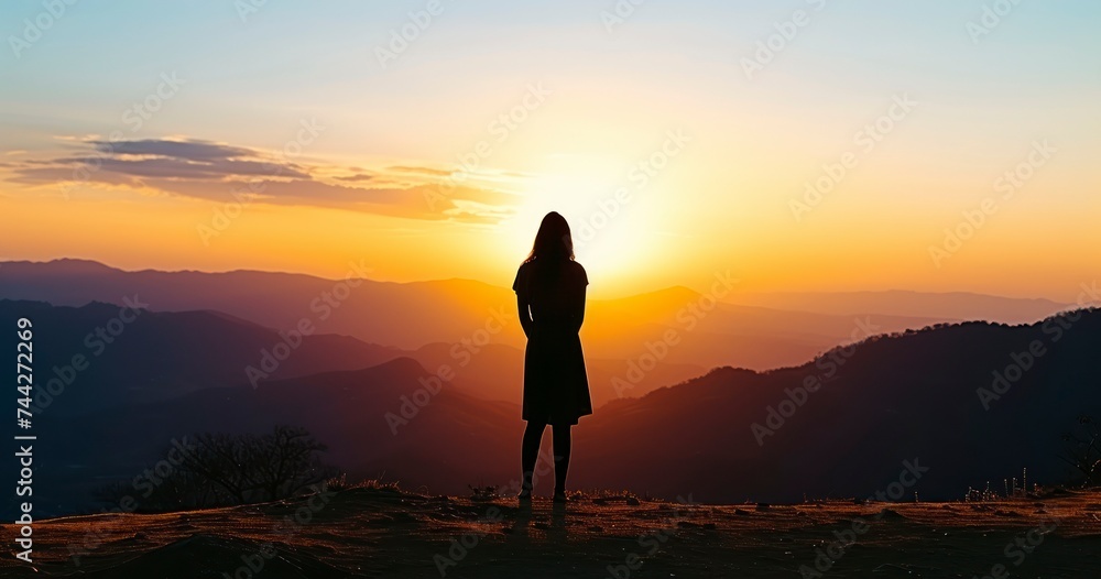 The Serene Silhouette of a Woman Standing on a Hill Against a Sunset Backdrop