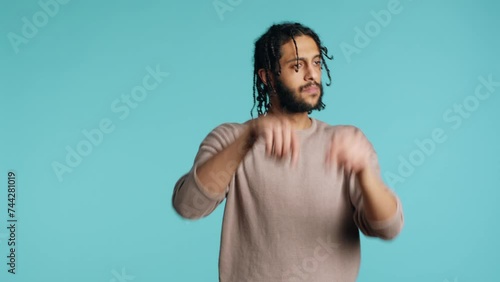 middle eastern conductor performing classical music concert following imaginary sheet music. Man doing delicate swinging hand motions, pretending to conduct orchestra, studio background, camera A photo