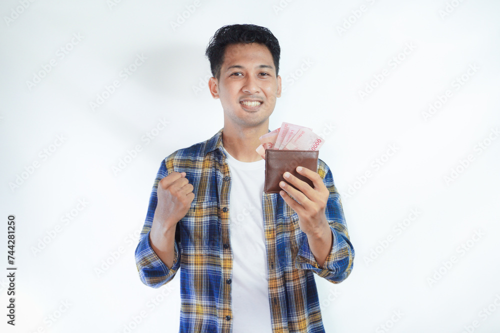 Adult Asian man showing excited face expression while holding his wallet full of money Adult Asian man showing excited face expression while holding his wallet full of money