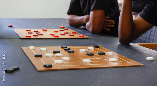 african american men with two boards playing, Nine men's morris strategy board game photo
