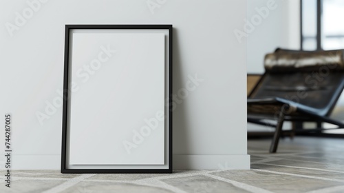 Blank vertical black poster frame standing on the floor against white wall in modern living room, empty picture frame mockup.