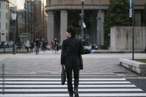 横断歩道を渡るビジネスマンの後ろ姿 © monzenmachi