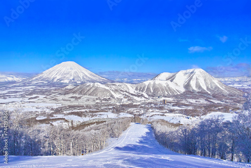 真冬の快晴の日本北海道のルスツスキー場、ゲレンデ内から見える羊蹄山とルスツスキーリゾートの景観
