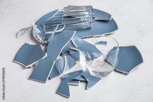 Broken plates and glasses on light background photo