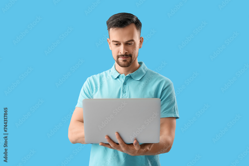 Handsome man using laptop on blue background Handsome man using laptop on blue background