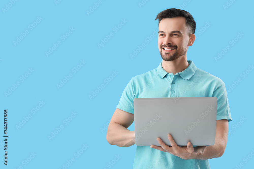 Handsome man using laptop on blue background Handsome man using laptop on blue background